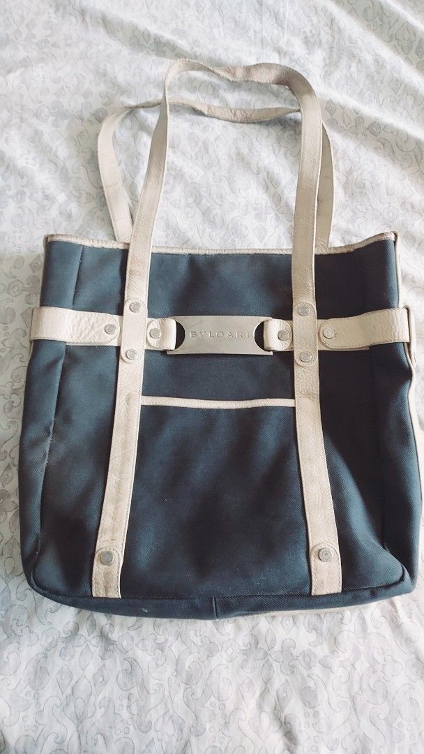 Bvlgari Black Canvas Tote Bag (Category: Tote Bags) located in Cavite. Submitted by bonita2230 (Listing ID 1470961967, Image 1). Description: - Authentic Bvlgari black canvas tote bag - Cream leather straps, trim, and front slip pocket - Silver metal front plate with Bvlgari logo engraving - Double shoulder straps detailed with metallic studs - Note: Shows visible signs of wear and patina on the leather handles and straps from regular use.