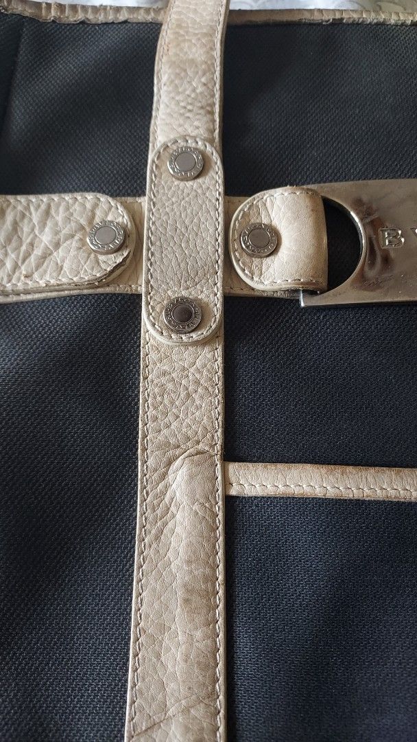 Bvlgari Black Canvas Tote Bag (Category: Tote Bags) located in Cavite. Submitted by bonita2230 (Listing ID 1470961967, Image 3). Description: - Authentic Bvlgari black canvas tote bag - Cream leather straps, trim, and front slip pocket - Silver metal front plate with Bvlgari logo engraving - Double shoulder straps detailed with metallic studs - Note: Shows visible signs of wear and patina on the leather handles and straps from regular use.