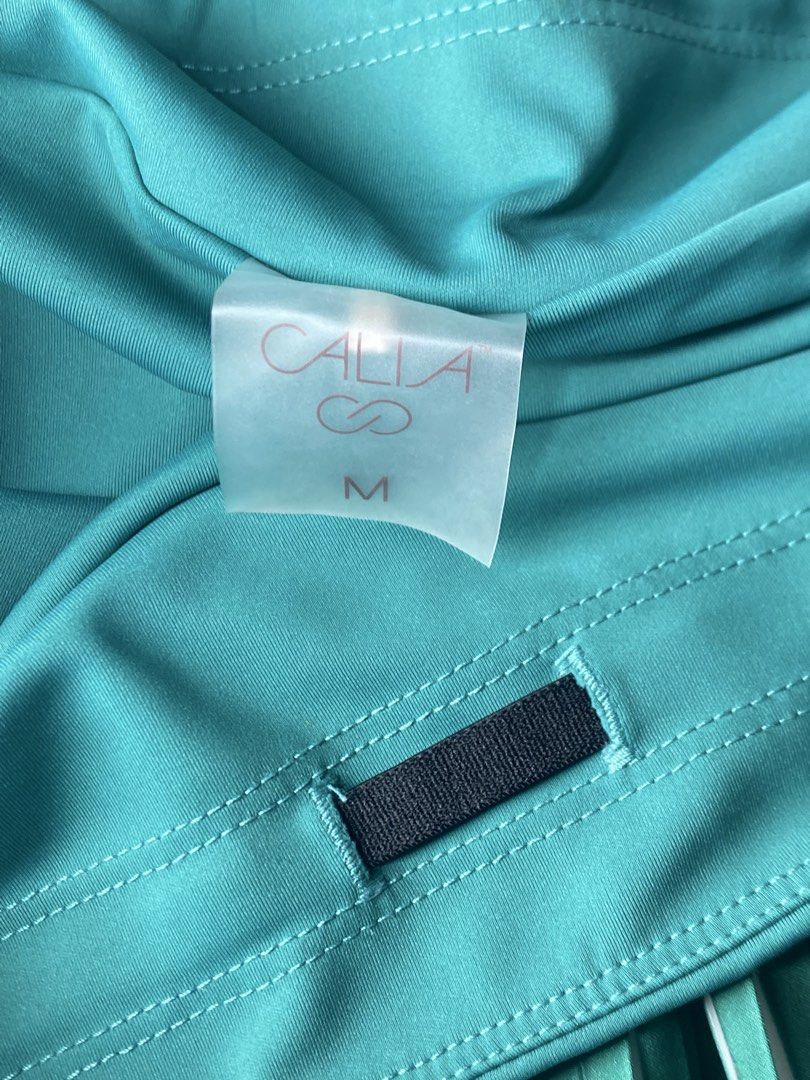 CALIA Green Pleated Athletic Skort Size M (Category: Activewear) located in Dagupan City. Submitted by vell25apparel (Listing ID 1470937445, Image 3). Description: - Brand: CALIA - Style: Athletic pleated skort with built-in shorts - Color: Teal green - Size: Medium - Features: Convenient side pockets on shorts and infinity logo emblem on waistband - Ideal for: Tennis, golf, workouts, and casual activewear.