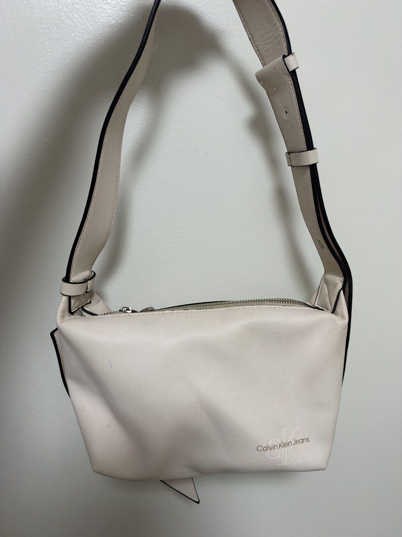 Calvin Klein Jeans Off-White Shoulder Bag (Category: Shoulder Bags) located in Manila. Submitted by cat-d526 (Listing ID 1470984364, Image 1). Description: - Brand: Calvin Klein Jeans - Color: Off-white - Closure: Zip top with silver-tone hardware and branded pull - Strap: Adjustable with buckle details - Logo: Debossed Calvin Klein Jeans logo on the front - Condition: Has noticeable scuffs and marks on the body and near the zipper area (priced a