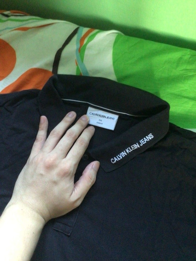Calvin Klein Jeans Polo Shirt (Category: Tshirts & Polo Shirts ) located in General Trias. Submitted by dunht (Listing ID 1471082546, Image 2). Description: - Brand: Calvin Klein Jeans - Color: Classic Black - Size: XXL (Slim Fit) - Material: 100% Premium Cotton (Made in Vietnam) - Design: Classic collar with printed brand lettering along the edge, two-button placket, short sleeves - Condition: Clean fabric with standard ribbed texture, inside ta