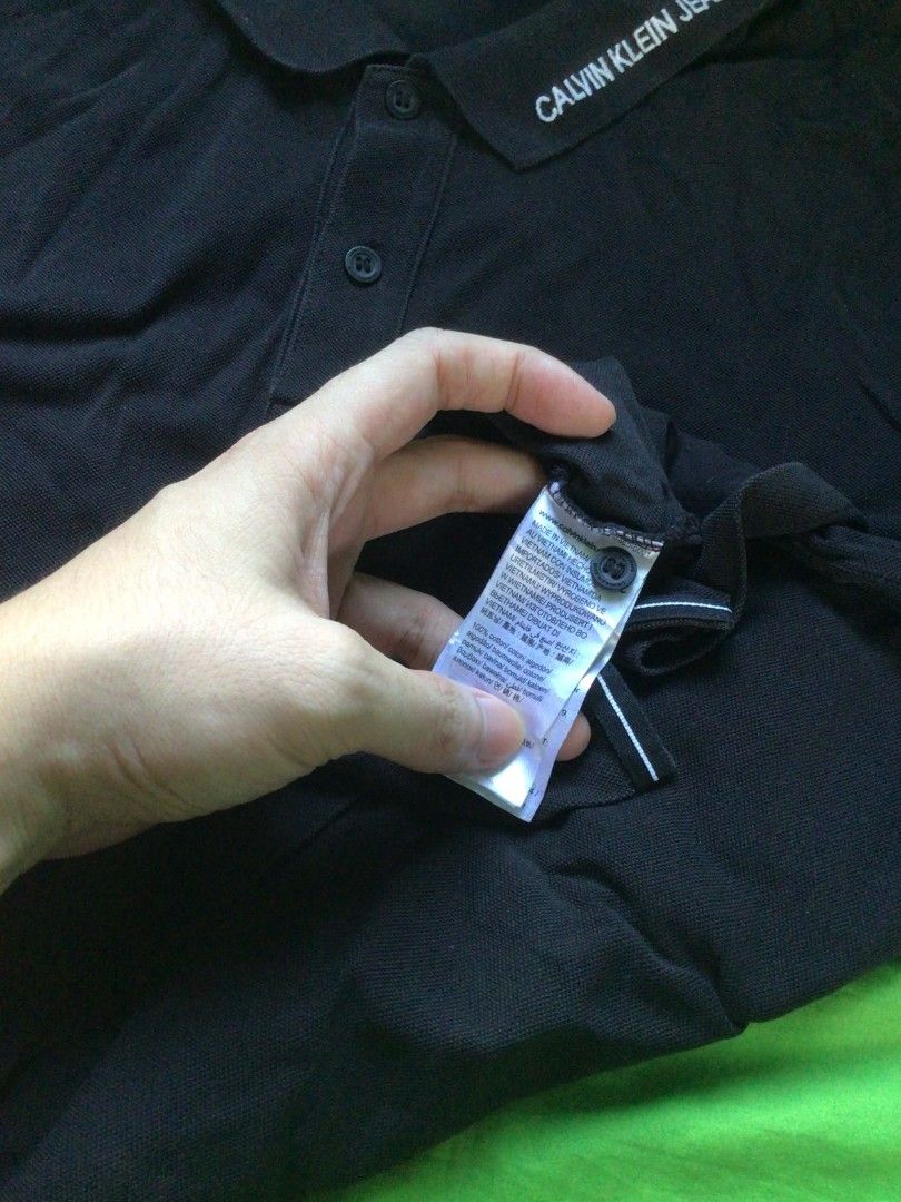 Calvin Klein Jeans Polo Shirt (Category: Tshirts & Polo Shirts ) located in General Trias. Submitted by dunht (Listing ID 1471082546, Image 3). Description: - Brand: Calvin Klein Jeans - Color: Classic Black - Size: XXL (Slim Fit) - Material: 100% Premium Cotton (Made in Vietnam) - Design: Classic collar with printed brand lettering along the edge, two-button placket, short sleeves - Condition: Clean fabric with standard ribbed texture, inside ta
