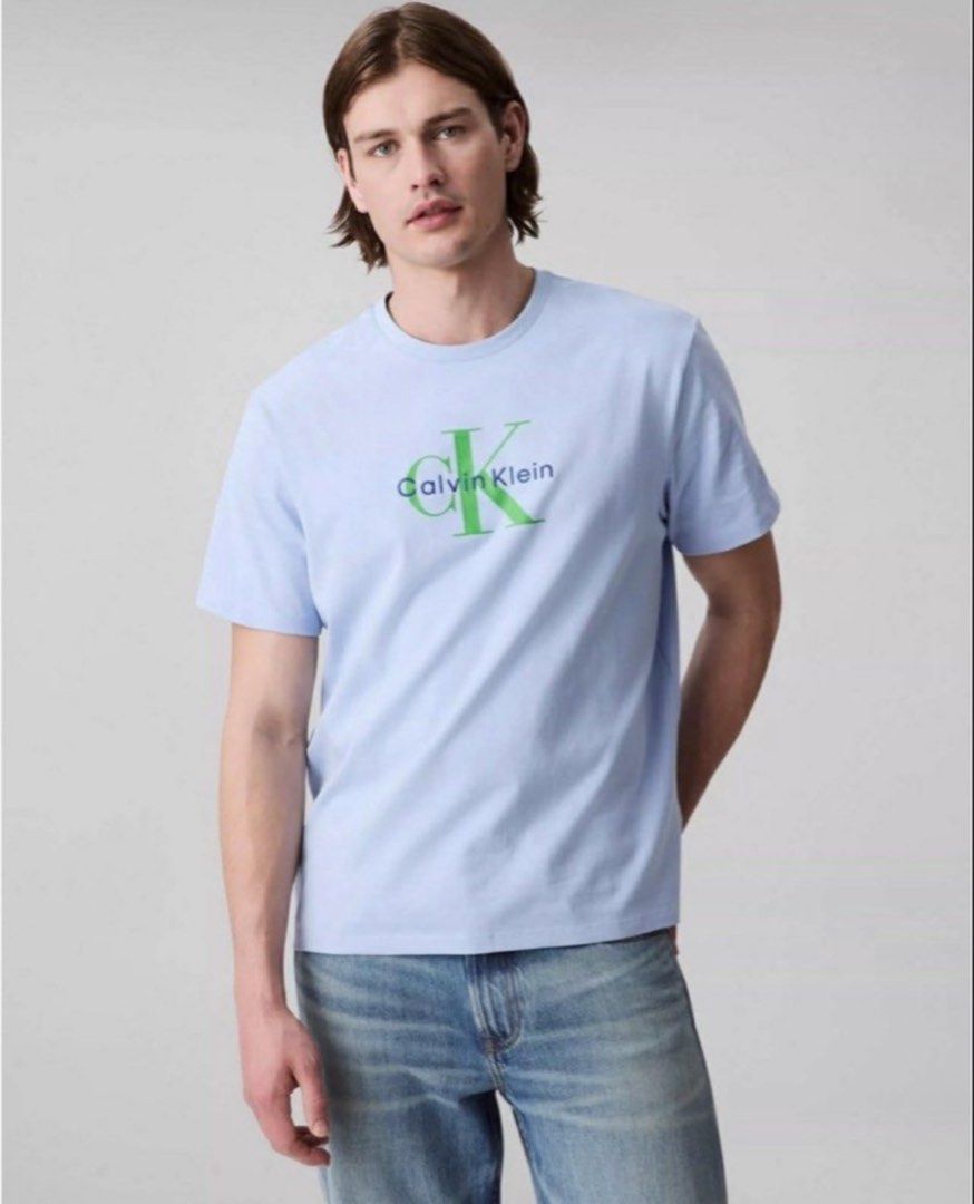 Calvin Klein Jeans T-Shirt Light Blue Medium (Category: Tshirts & Polo Shirts ) located in Pasay City. Submitted by szepter (Listing ID 1470951640, Image 1). Description: - Brand: Calvin Klein Jeans - Condition: Brand new with tags (BNWT), never worn - Size: Medium - Color: Light blue with large green and navy chest logo - Material: Soft cotton - Style: Classic crew neck, casual everyday wear - Note: Pit-to-pit measurement available in photos.