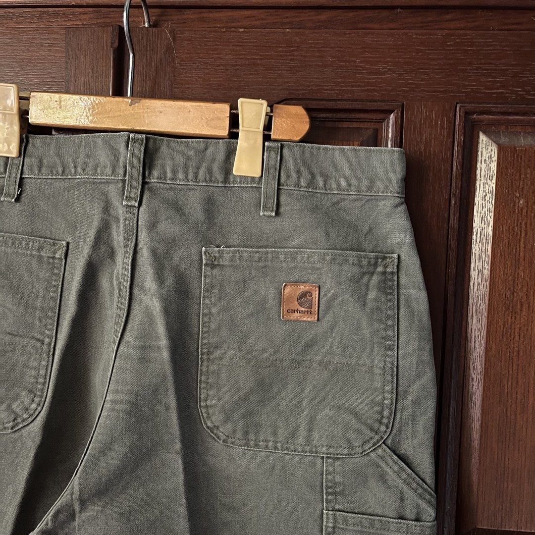 Carhartt moss green carpenter shorts (Category: Shorts) located in Manila. Submitted by thriftyyyyy. (Listing ID 1470989975, Image 3). Description: - Brand/Item: Carhartt Canvas Utility Shorts - Color: Olive Green - Features: Double front pockets, hammer loop, and tool pockets - Details: Classic leather logo patch on the right back pocket with button fly closure - Condition: Rugged workwear style with some minor surface marks and faint spotting f