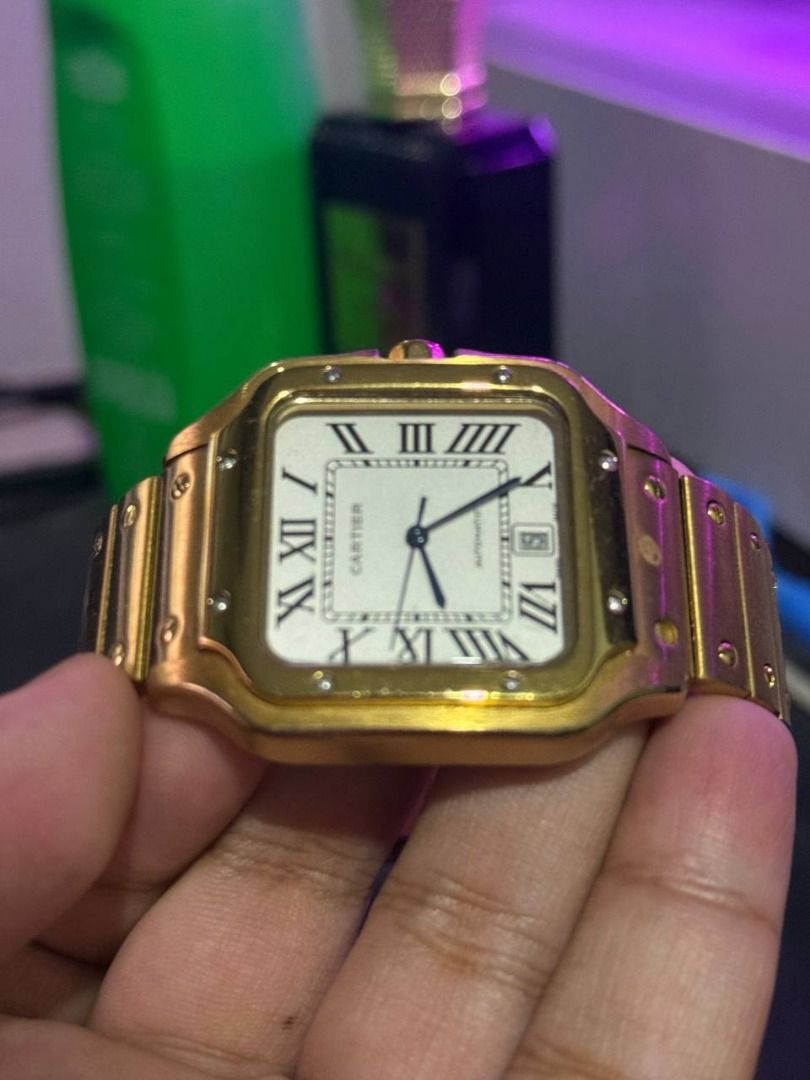Cartier Santos Automatic Gold Watch (Category: Luxury Watches) located in Binan City. Submitted by calvin654132317 (Listing ID 1471101793, Image 2). Description: - Authentic Gold Cartier Santos automatic watch - White dial with classic black Roman numerals and striking blue hands - Date window conveniently located at the 6 o'clock position - Signature blue cabochon stone on the crown - Distinct screw details along the bezel and linked bracelet wi