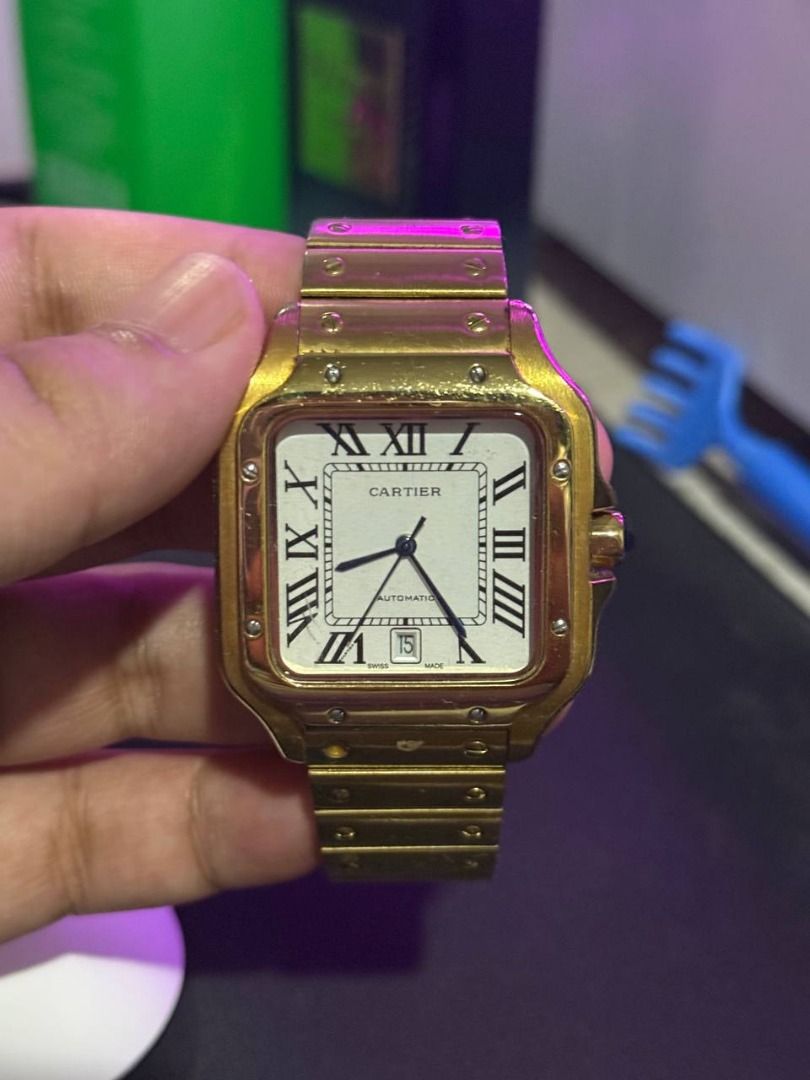 Cartier Santos Automatic Gold Watch (Category: Luxury Watches) located in Binan City. Submitted by calvin654132317 (Listing ID 1471101793, Image 1). Description: - Authentic Gold Cartier Santos automatic watch - White dial with classic black Roman numerals and striking blue hands - Date window conveniently located at the 6 o'clock position - Signature blue cabochon stone on the crown - Distinct screw details along the bezel and linked bracelet wi