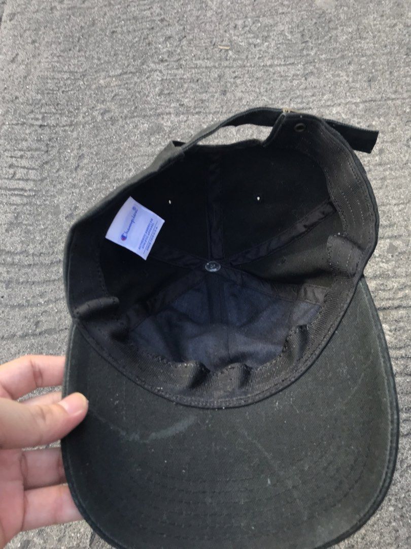 Champion Black Baseball Cap with Embroidered Logo (Category: Caps & Hats) located in Imus. Submitted by yoboi.04 (Listing ID 1471005124, Image 3). Description: - Brand: Champion - Color: Classic Black - Design: Six-panel construction with curved brim - Branding: Embroidered logo on the front, small patch on the side, and branded interior tag - Fit: Adjustable strapback with metal buckle - Condition: Shows minor dust and light wear on the fabric s