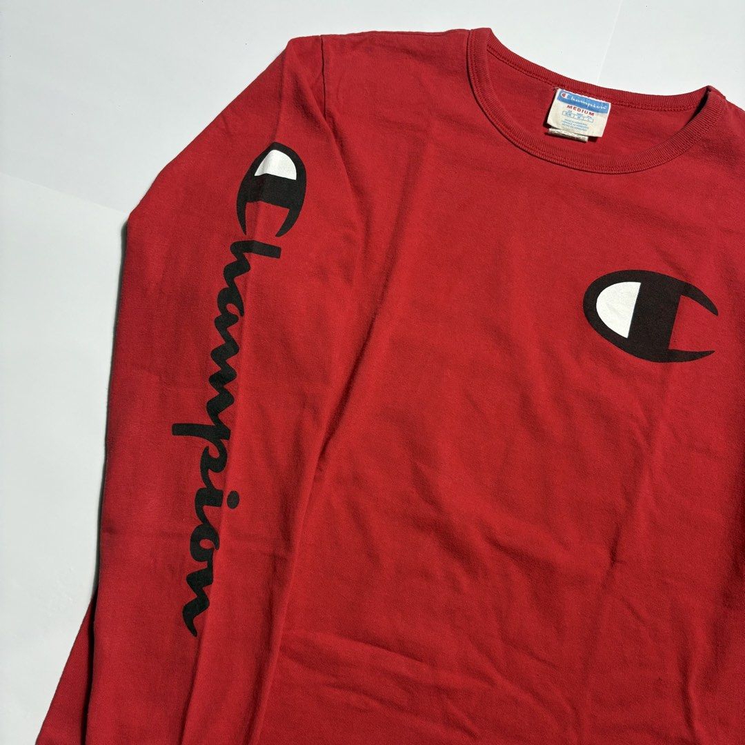Champion Red Long Sleeve T-Shirt Medium (Category: Tshirts & Polo Shirts ) located in San Fernando. Submitted by lumang_gamit (Listing ID 1471065457, Image 2). Description: - Brand: Champion - Color: Red - Size: Medium (Made in Honduras) - Design: Big C logo on chest, text graphic on right sleeve, and embroidered patch on left cuff - Details: Ribbed collar and cuffs for a comfortable fit - Condition: Excellent, ready to wear.