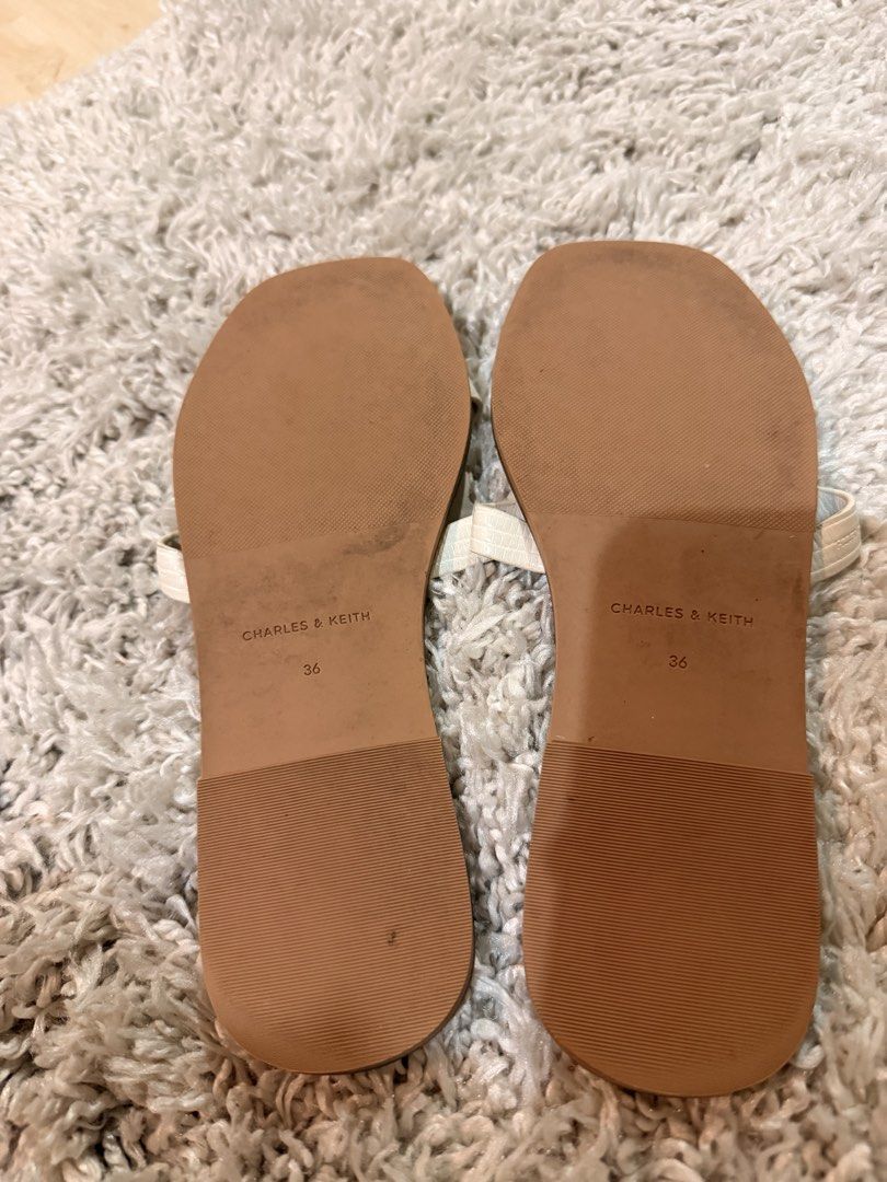 Charles & Keith White Sandals Size 36 (Category: Flats & Sandals) located in Mandaluyong City. Submitted by riz_040521 (Listing ID 1470974110, Image 3). Description: - Brand: Charles & Keith - Type: Flat sandals - Color: White - Size: 36 / 230 - Style: Slip-on with cutout straps and textured pattern - Origin: Made in Malaysia - Condition: Clean footbeds with visible branding, minor wear on soles - bought in Singapore 🇸🇬 .
