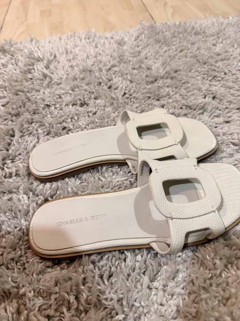 Charles & Keith White Sandals Size 36 (Category: Flats & Sandals) located in Mandaluyong City. Submitted by riz_040521 (Listing ID 1470974110, Image 2). Description: - Brand: Charles & Keith - Type: Flat sandals - Color: White - Size: 36 / 230 - Style: Slip-on with cutout straps and textured pattern - Origin: Made in Malaysia - Condition: Clean footbeds with visible branding, minor wear on soles - bought in Singapore 🇸🇬 .