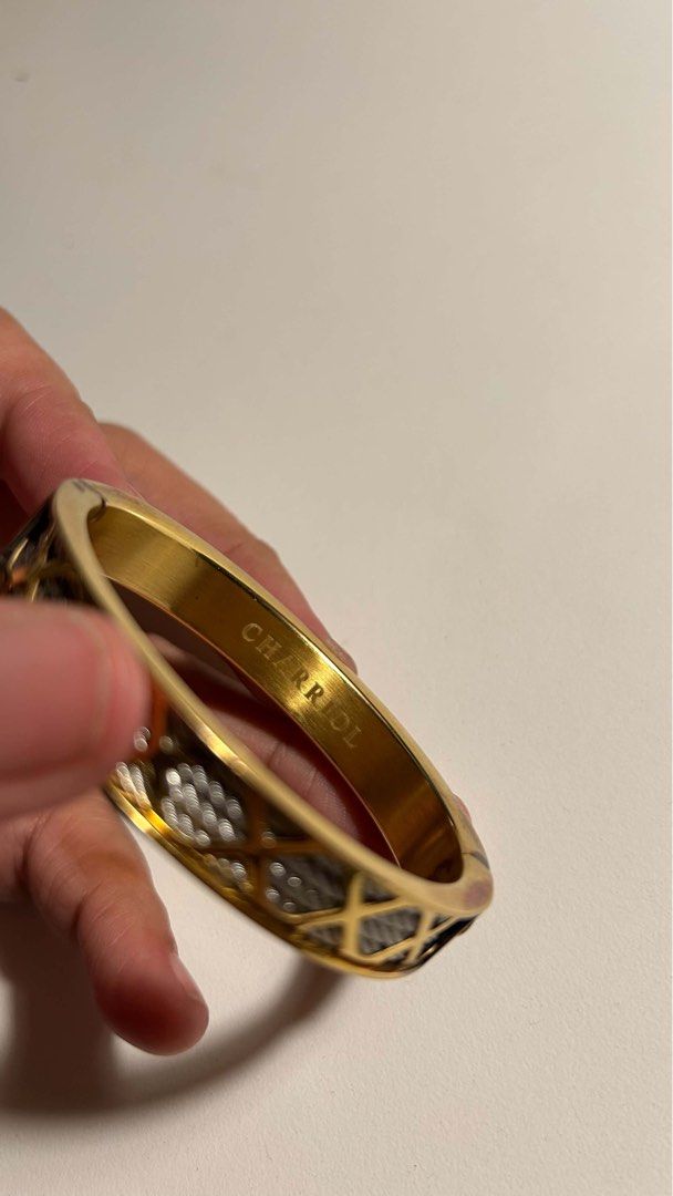 Charriol Gold Bangle Bracelet (Category: Bracelets) located in Paranaque City. Submitted by declutterby4angels (Listing ID 1471035022, Image 3). Description: - Authentic Charriol gold-tone metal bangle - Signature textured cable design along the outer band - Convenient hinged side opening for easy wear - Brand name engraved on the interior - Condition: Shows visible tarnishing and wear along the edges, particularly near the hinge (please manage e