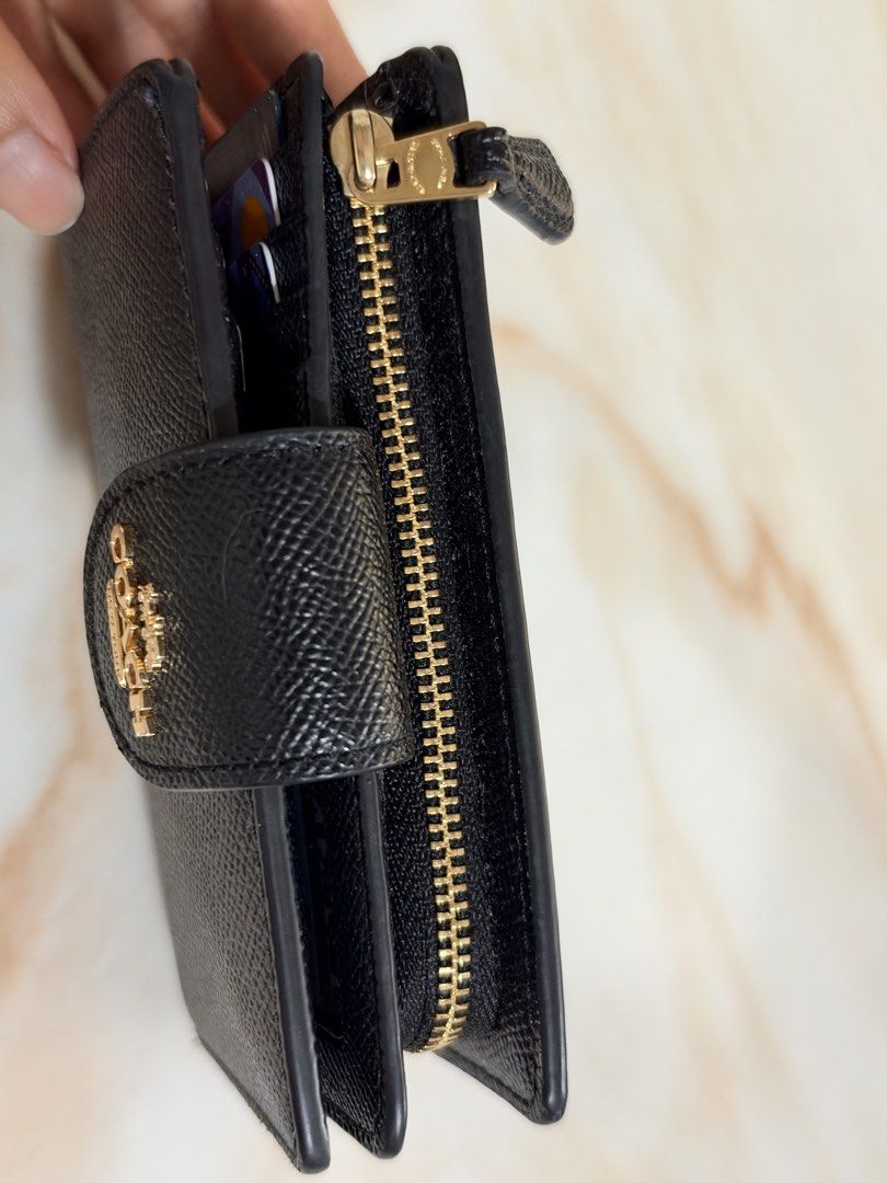 Coach Black Leather Medium Wallet (Category: Wallets & Card holders) located in Taguig. Submitted by triaa_ (Listing ID 1470983273, Image 2). Description: - Authentic black Coach wallet crafted from durable crossgrain leather - Elegant gold-tone hardware with a secure front flap snap closure - Multiple interior card slots to organize your essentials - Convenient zipped coin pocket along the side - Clean black interior lining - Compact design that