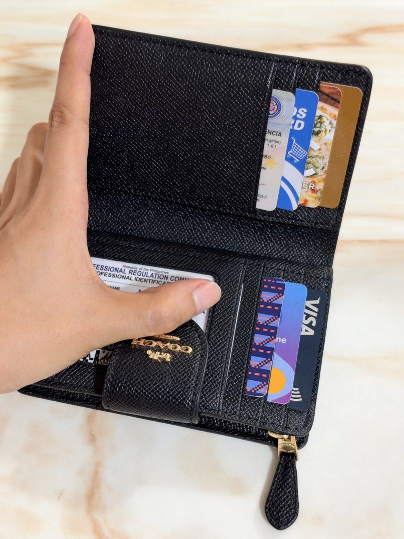 Coach Black Leather Medium Wallet (Category: Wallets & Card holders) located in Taguig. Submitted by triaa_ (Listing ID 1470983273, Image 3). Description: - Authentic black Coach wallet crafted from durable crossgrain leather - Elegant gold-tone hardware with a secure front flap snap closure - Multiple interior card slots to organize your essentials - Convenient zipped coin pocket along the side - Clean black interior lining - Compact design that