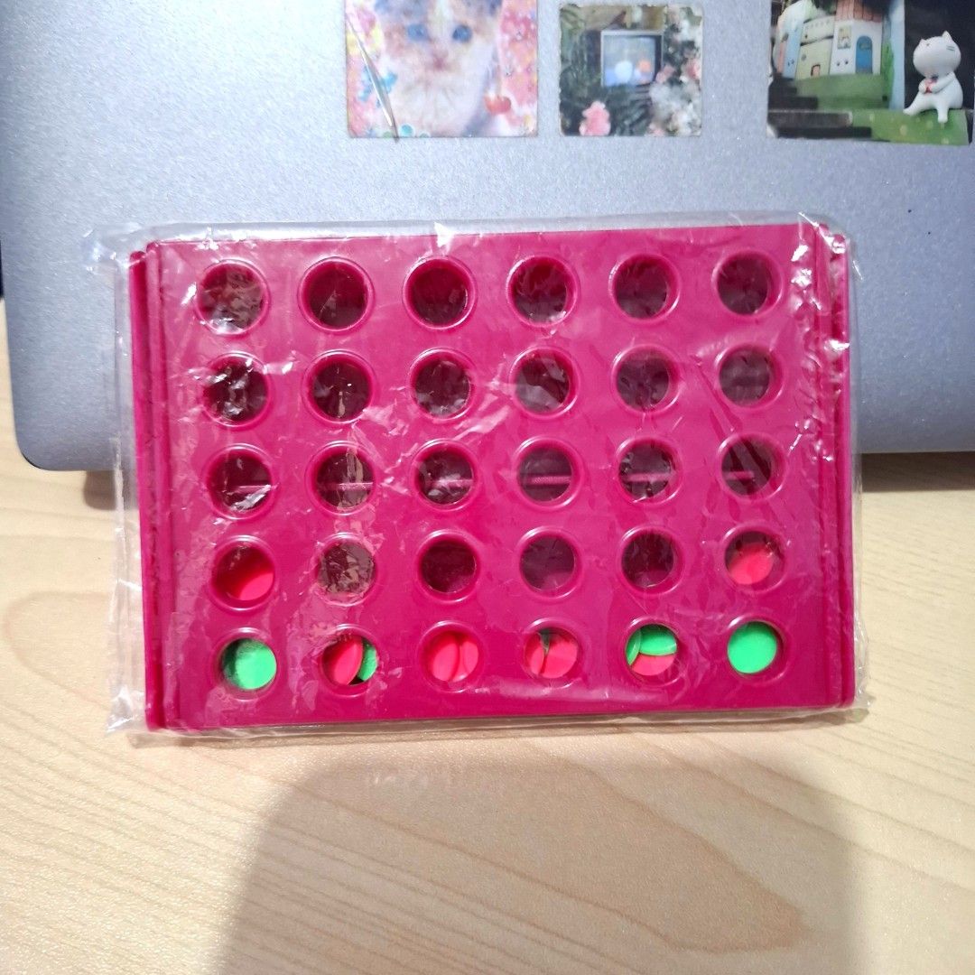 Connect Four Board Game Toy (Category: Board Games & Puzzles) located in Quezon City. Submitted by ana-chan (Listing ID 1471047266, Image 2). Description: - Game: Miniature Connect Four strategy game - Condition: Brand new, wrapped in original plastic packaging - Design: Cute pink grid frame with double-sided green and red playing chips - Feature: Quick-release bottom for instant piece reset - Portability: Compact travel size, perfect for trips a