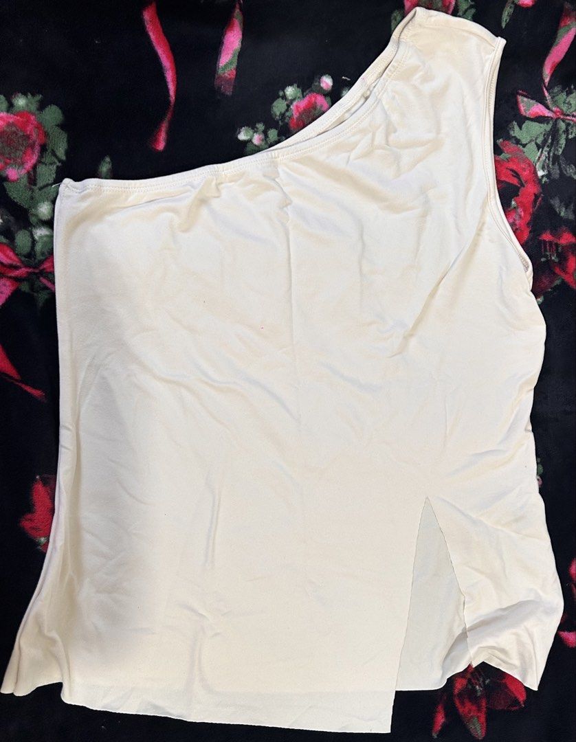 Cream One-Shoulder Split Hem Top (Category: Sleeveless) located in Manila. Submitted by coffeeislyf (Listing ID 1470989828, Image 2). Description: - Color: Cream - Style: Trendy one-shoulder neckline with a relaxed fit - Design: Asymmetric hem featuring a side split for easy tucking - Fabric: Lightweight and breathable, perfect for warm weather or layering - Condition: Clean and ready to wear.