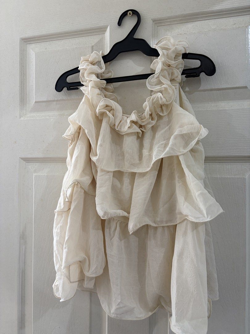 Cream Ruffle Layered Sleeveless Blouse (Category: Sleeveless) located in Quezon City. Submitted by elleinxx (Listing ID 1471052506, Image 1). Description: - Cream sleeveless top with heavy ruffle layers - Lightweight textured fabric with a loose, flowy fit - Perfect for tucking into high-waisted jeans or skirts - Clean condition with no stains or pulled threads - From a smoke-free home.