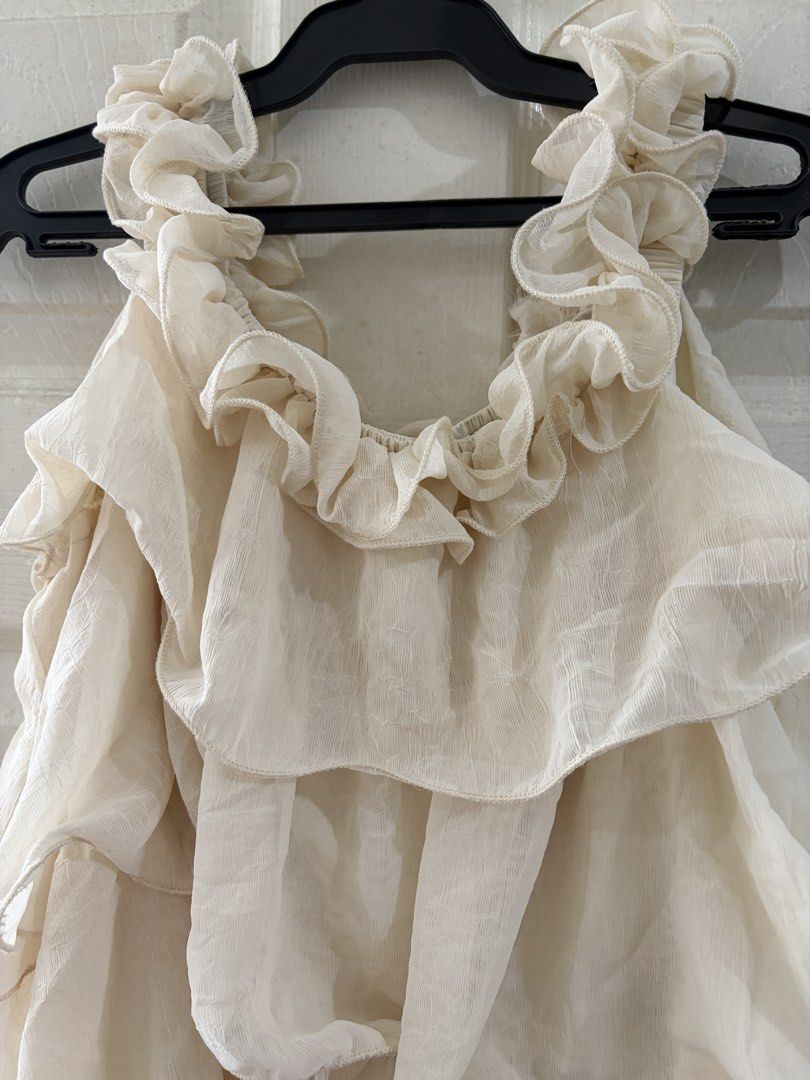Cream Ruffle Layered Sleeveless Blouse (Category: Sleeveless) located in Quezon City. Submitted by elleinxx (Listing ID 1471052506, Image 3). Description: - Cream sleeveless top with heavy ruffle layers - Lightweight textured fabric with a loose, flowy fit - Perfect for tucking into high-waisted jeans or skirts - Clean condition with no stains or pulled threads - From a smoke-free home.