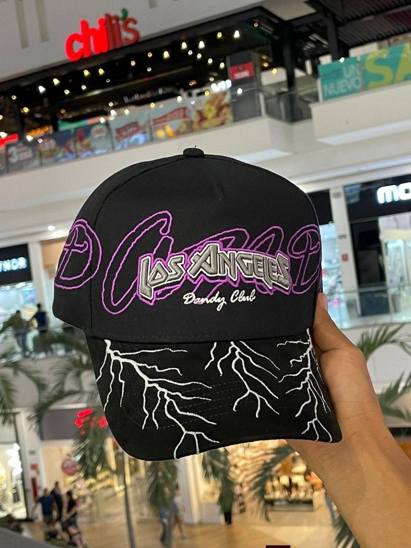 Dandy Hats Los Angeles Lightning Cap Black Purple (Category: Caps & Hats) located in Dipolog. Submitted by just_thriftfinds (Listing ID 1471060423, Image 1). Description: Black baseball cap from Dandy Hats. Los Angeles lettering embroidered across the front with purple outline and Dandy Club text. Brim features white lightning bolt embroidery. Purple inner lining with printed branding throughout and branded taping. Adjustable strap in the back..