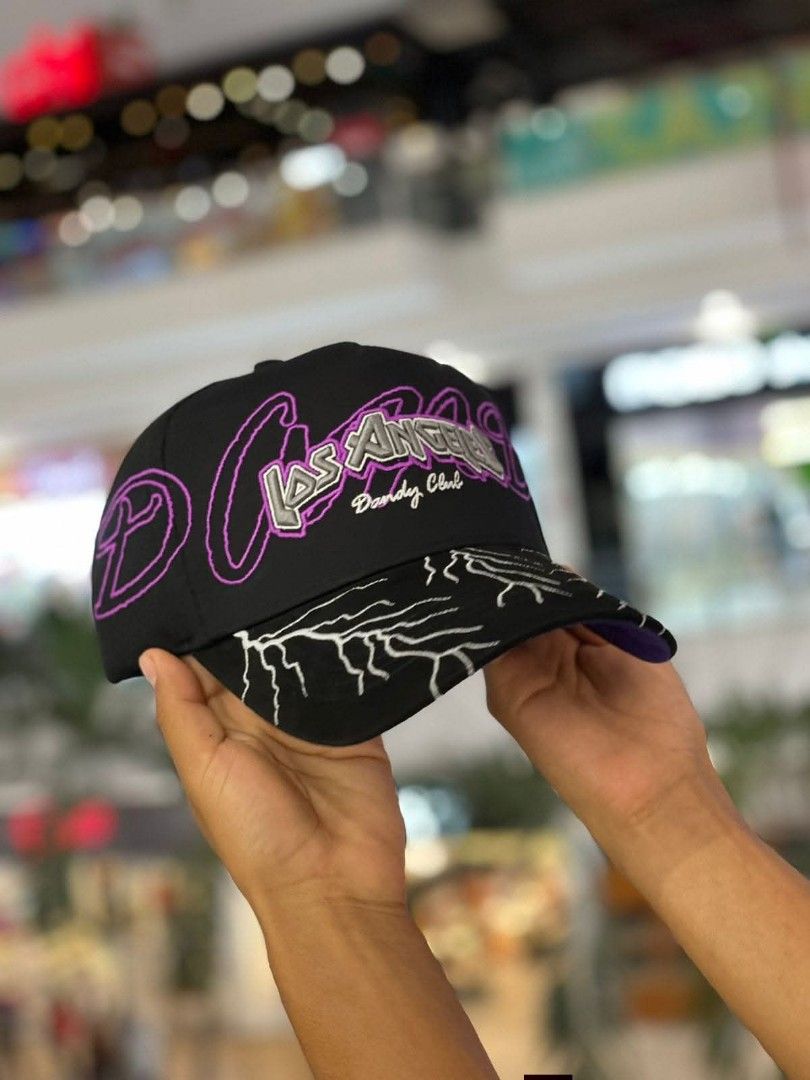 Dandy Hats Los Angeles Lightning Cap Black Purple (Category: Caps & Hats) located in Dipolog. Submitted by just_thriftfinds (Listing ID 1471060423, Image 3). Description: Black baseball cap from Dandy Hats. Los Angeles lettering embroidered across the front with purple outline and Dandy Club text. Brim features white lightning bolt embroidery. Purple inner lining with printed branding throughout and branded taping. Adjustable strap in the back..