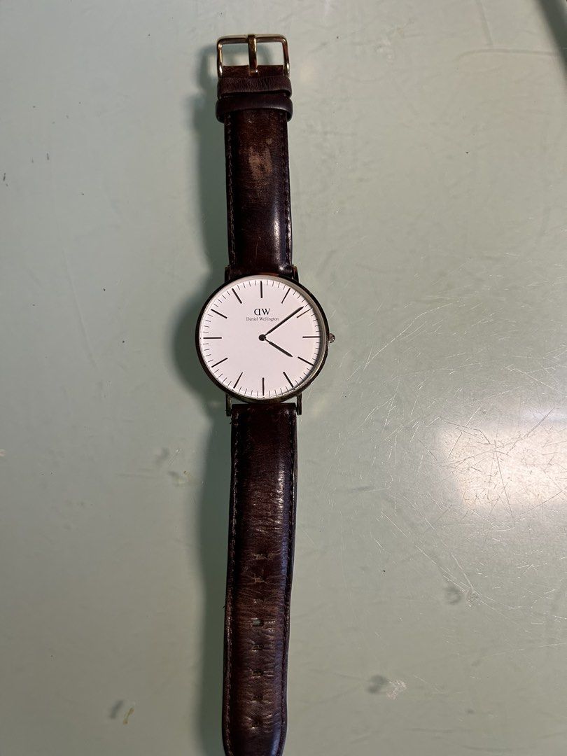 Daniel Wellington Classic Watch Dark Brown Leather Strap (Category: Men's Watches) located in Cavite. Submitted by mamamia73 (Listing ID 1471082262, Image 1). Description: - Brand: Daniel Wellington - Case Size: 40 (measured) - Color: Rose gold case with a clean white dial - Strap: Dark brown genuine leather (Note: shows heavy wear and creasing near the top buckle area) - Design: Classic minimalist face with simple line markers - Details: Brand t