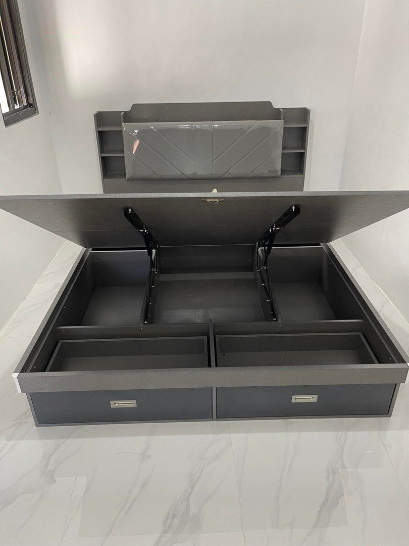 Dark Grey Storage Bed Frame with Headboard and Drawers (Category: Bed Frames & Mattresses) located in Calamba. Submitted by missarc (Listing ID 1471067546, Image 2). Description: Dark grey wooden bed frame featuring hydraulic lift storage underneath. Headboard built with upholstered padded cushion and side shelving compartments. Two pull-out drawers integrated at the foot of the base. Clean dark wood finish throughout. Mattress not included..