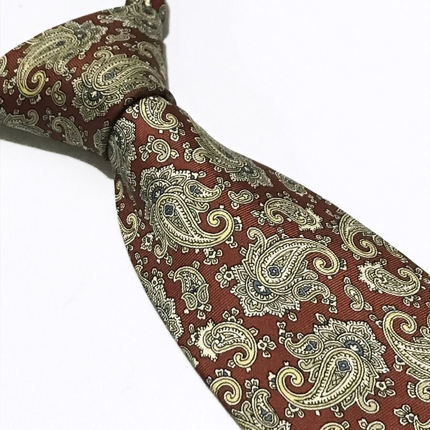 DAS Cravatte Red Paisley Neck Tie (Category: Ties) located in Taguig. Submitted by retrogaze (Listing ID 1470986622, Image 1). Description: This vintage 100% silk necktie by DAS Cravatte features a rich rust-red base woven in a subtle horizontal repp texture. The entire blade is adorned with an intricate, dense paisley foulard pattern showcasing swirling teardrop motifs and floral flourishes in soft champagne gold, cream, slate blue, and sage gre