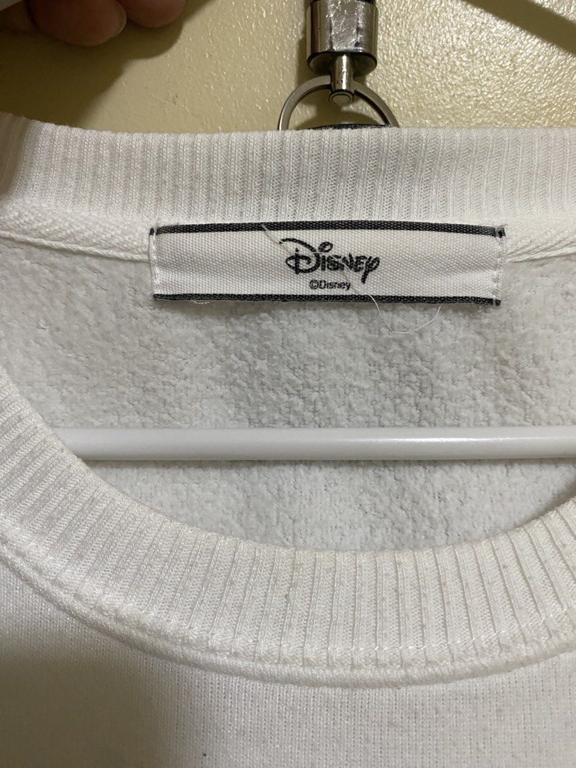 Disney Mickey Mouse White Sweatshirt (Category: Coats, Jackets and Outerwear) located in Silang. Submitted by iamjhestine (Listing ID 1471070344, Image 3). Description: - Authentic Disney Mickey Mouse sweatshirt in white - Features a large graphic print inside the letter 'M' with 'MICKEY' lettering - Cozy soft fleece interior lining - Classic ribbed crewneck, cuffs, and hem - Flaw: Noticeable small yellow stain near the bottom of the graphic prin