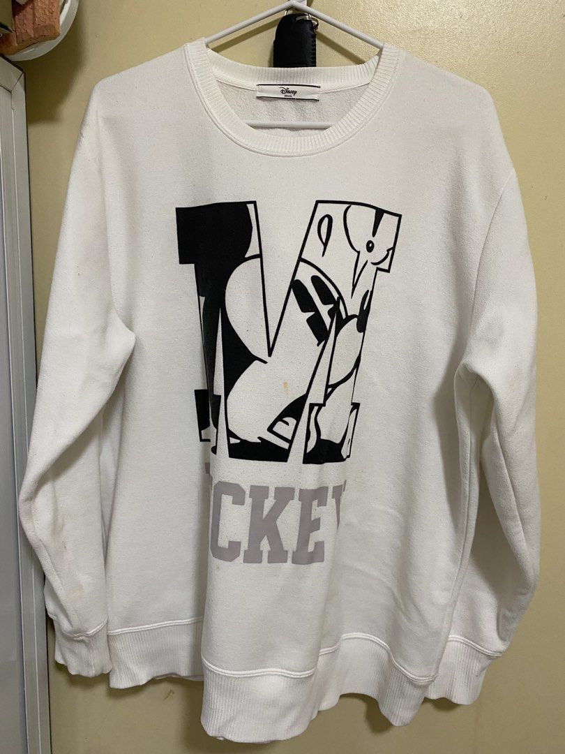 Disney Mickey Mouse White Sweatshirt (Category: Coats, Jackets and Outerwear) located in Silang. Submitted by iamjhestine (Listing ID 1471070344, Image 1). Description: - Authentic Disney Mickey Mouse sweatshirt in white - Features a large graphic print inside the letter 'M' with 'MICKEY' lettering - Cozy soft fleece interior lining - Classic ribbed crewneck, cuffs, and hem - Flaw: Noticeable small yellow stain near the bottom of the graphic prin