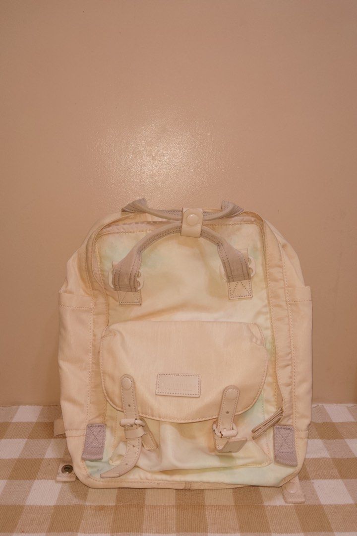 Doughnut Macaroon Backpack Cream (Category: Backpacks) located in Silang. Submitted by sashiecart (Listing ID 1470933952, Image 1). Description: - Color: Cream - Style: Doughnut Macaroon daily casual backpack - Features: Top carry handles with snap button keeper, front pocket with dual buckle straps, side slip pockets, and adjustable shoulder straps - Storage: Spacious interior with plenty of room for daily essentials - Condition: Shows some fadi