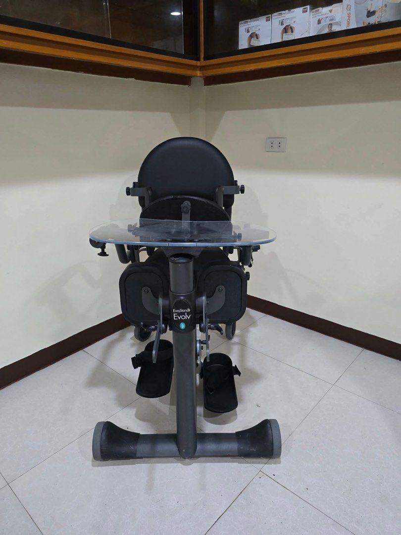 EasyStand Evolv Mobility Stander with Tray (Category: Braces, Support & Protection) located in Manila. Submitted by calmdolphin.87b0e4 (Listing ID 1470954437, Image 3). Description: - EasyStand Evolv electric standing frame with battery pack at the base - Heavy-duty dark grey steel frame equipped with 4 smooth-rolling wheels for easy mobility - Includes clear tray table, comfortable padded seat, backrest, knee supports, and foot straps - Fully ad