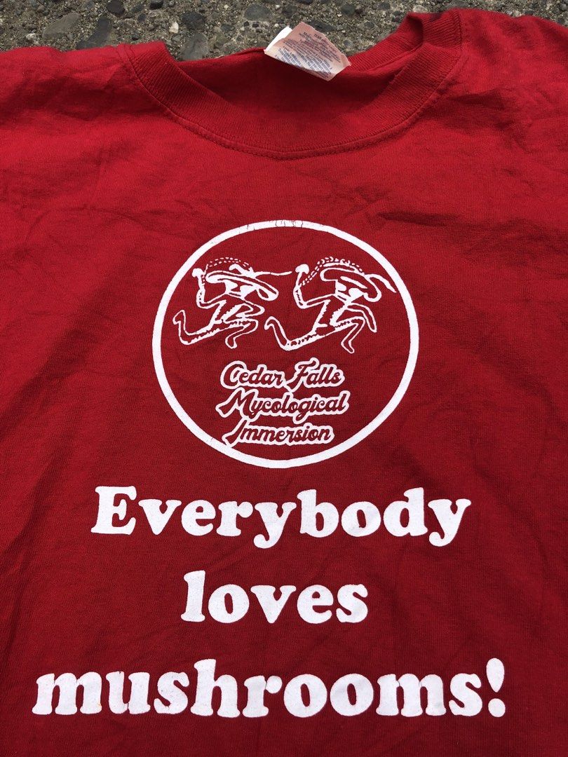 Everybody loves mashrooms (Category: Tshirts & Polo Shirts ) located in San Jose. Submitted by mightycloud-7dc0 (Listing ID 1470976283, Image 2). Description: - Brand/Style: Port & Company bright red graphic t-shirt - Size: Large - Design: Front circle logo reads 'Cedar Falls Mycological Immersion' with 'Everybody loves mushrooms' underneath - Origin: Made in Honduras - Flaws: Noticeable dark ink stains and fabric tears near the right sleeve hem 