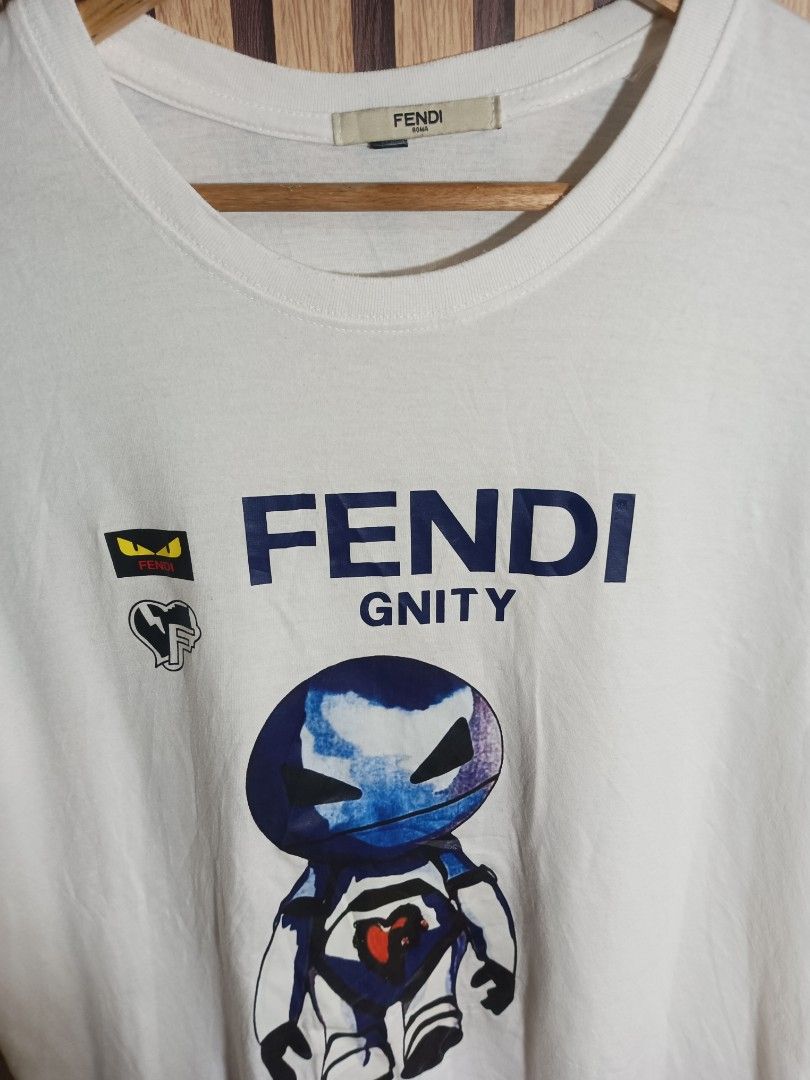 Fendi Gnity Robot Graphic White T-Shirt (Category: Shirts) located in Manila. Submitted by delavinjor93182 (Listing ID 1471114791, Image 2). Description: - Brand: Fendi - Color: White with blue robot graphic - Key Features: Iconic monster eyes patch and heart chest accent - Details: Crew neck, short sleeves, straight hem, Fendi Roma collar tag - Condition: Clean and crisp.