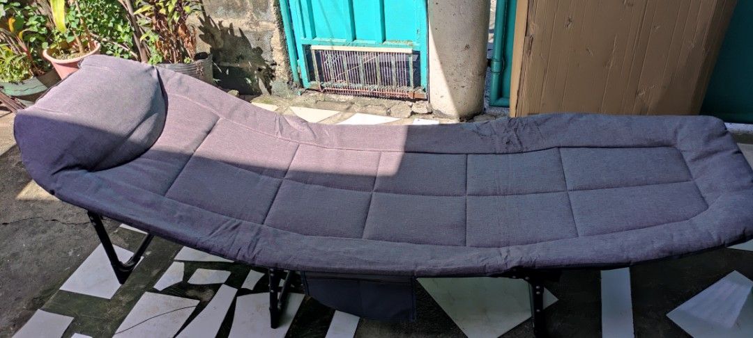 Foldable Grey Lounge Bed Cot with Pillow (Category: Outdoor Furniture) located in Dasmarinas. Submitted by jdelacruz0728 (Listing ID 1471085276, Image 1). Description: - Color/Material: Grey fabric with a sturdy black metal frame - Features: Built-in pillow section for head support - Portability: Folds compactly in half for easy storage and transport - Condition: Minor fraying on the top edge near the middle; fabric shows light wear - Usage: Grea