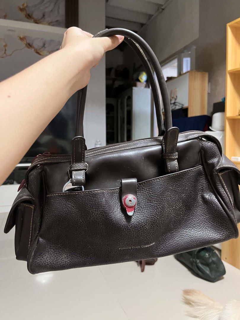 Fortune Duck Collection Brown Leather Handbag (Category: Luxury Bags & Wallets) located in General Trias. Submitted by starberrii (Listing ID 1470978181, Image 1). Description: - Brand/Collection: Fortune Duck Collection - Color/Material: Dark brown leather with fabric lining - Design: Structured everyday handbag with dual top handles - Closure & Pockets: Decorative red lock front pocket and multiple zipped compartments inside and out - Condition