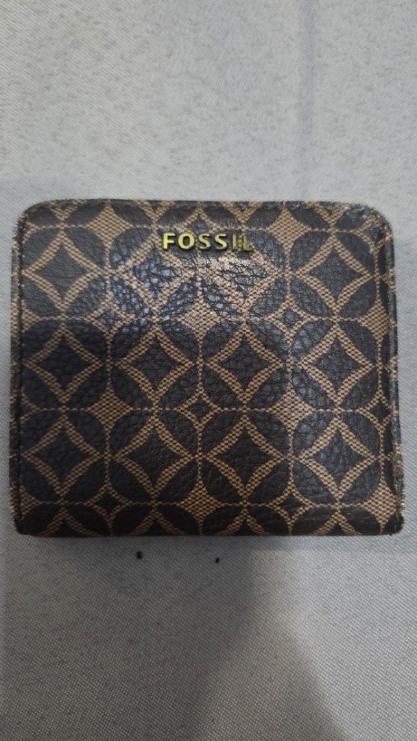 Fossil Monogram Print Bi-fold Wallet (Category: Wallets & Card holders) located in Quezon City. Submitted by kctheexplorer05 (Listing ID 1471085968, Image 1). Description: Fossil bi-fold wallet in dark brown monogram pattern. Gold-tone logo stamped on front. Interior includes card slots, ID window, and cash compartment. Back side features a zippered coin pocket. Compact size fits easily into handbags and pockets. Brass-tone hardware throughout. s