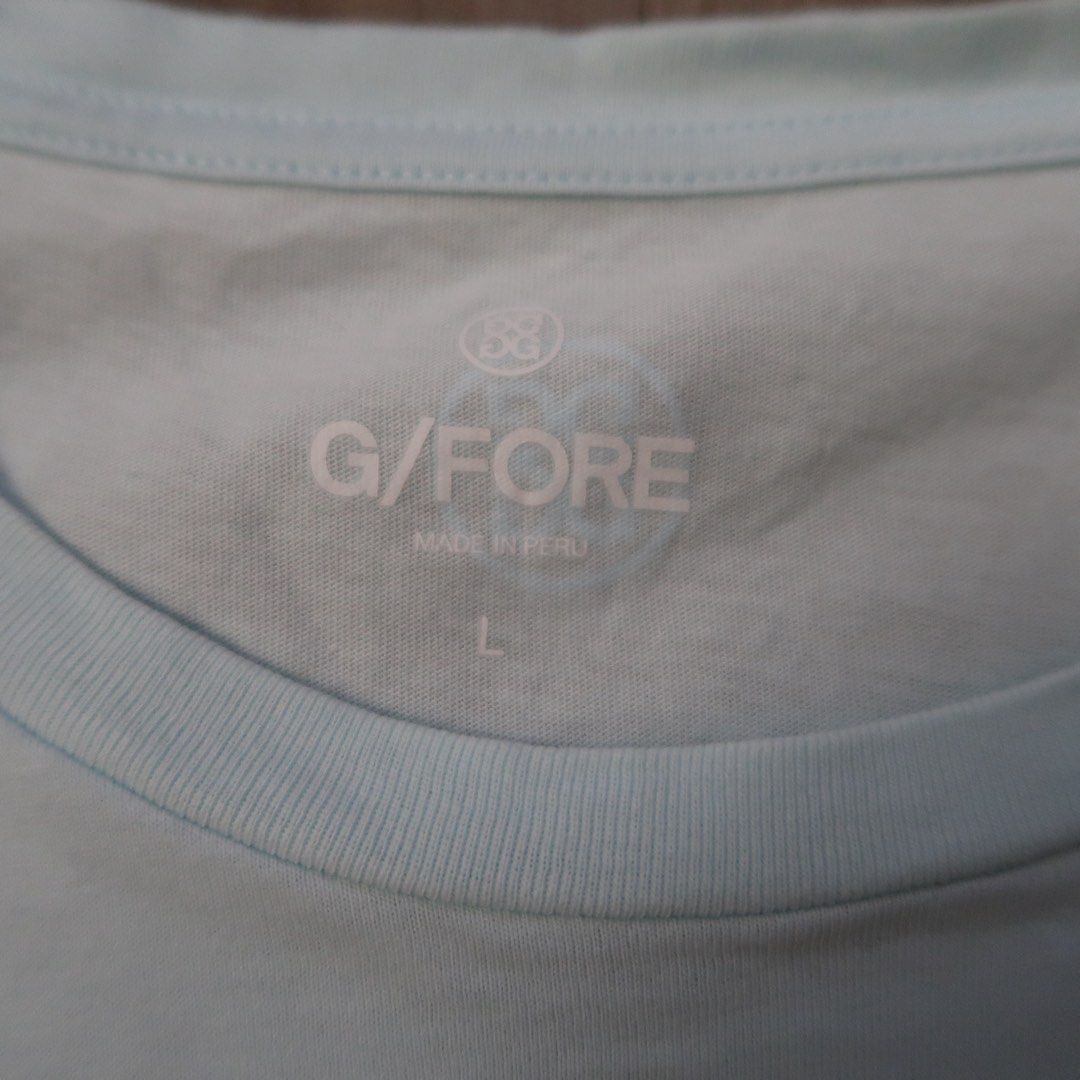 G/FORE Light Blue Logo T-Shirt Size L (Category: Tshirts & Polo Shirts ) located in Manila. Submitted by mixi_lexi (Listing ID 1471043105, Image 2). Description: - Brand: G/FORE - Color: Light Blue - Size: L (printed inside collar with brand mark) - Design: Big logo stamped across the chest - Details: Short sleeves, crew neck - Origin: Made in Peru.