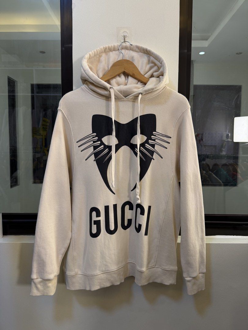 Gucci (“Manifesto” Collection) Pullover Hooded Sweatshirt (Category: Coats, Jackets and Outerwear) located in Paranaque City. Submitted by preluxeshop_ph (Listing ID 1471014114, Image 2). Description: Brand: Gucci (“Manifesto” Collection) •Style: Pullover Hooded Sweatshirt / Oversized Hoodie •Color: Off-White / Cream •Design Features: Black printed carnival mask graphic and bold “GUCCI” branding on the front, printed “THE MASK AS A CUT BETWEEN VI