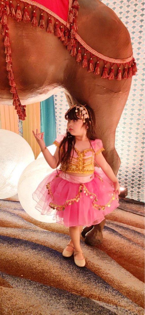 Hailey & Co Jasmine S6 (Category: Babies & Kids Fashion) located in Daraga. Submitted by iamsupershein (Listing ID 1470939015, Image 2). Description: - Bright pink princess costume with intricate gold embroidery - Two-piece set including a top and a layered tulle skirt with dangling coin trim - Features cute short sheer puff sleeves - Comes with a matching headpiece - Worn only once, excellent and clean condition - Ideal for themed events, partie