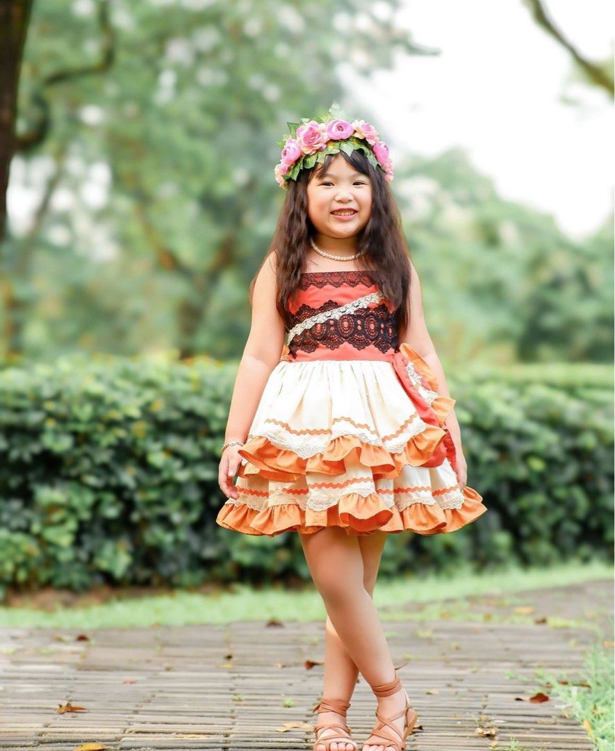 Hailey & Co Moana Dress Size 4 (Category: Babies & Kids Fashion) located in Daraga. Submitted by iamsupershein (Listing ID 1470938883, Image 1). Description: - Color & Style: Orange and cream tiered dress with layered ruffles - Unique Details: Black lace bodice accent and cross-body strap design - Bonus Item: Includes a matching pink floral crown headpiece - Perfect For: Themed parties, cosplay, and fun dress-up play - Fit: Comfortable for young 