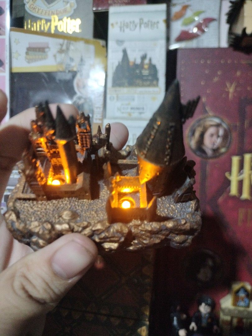 Harry Potter Hogwarts Castle Mini Figurine with Light (Category: Figurines & Statues) located in Paranaque City. Submitted by chechein_shop (Listing ID 1470967334, Image 2). Description: - Official-style miniature Hogwarts castle replica from Harry Potter - Features built-in glowing lights inside the towers for a magical effect - Detailed textured rocky base for realistic display - Compact size, ideal for desk or shelf decoration - Perfect collec