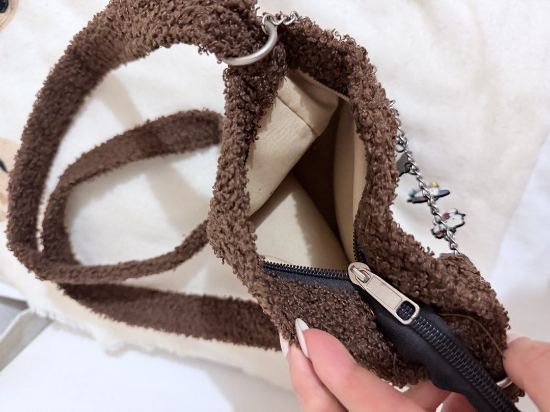 Hello Kitty brown fluffy crossbody bag with charm chain (Category: Cross-body Bags) located in Taguig. Submitted by mengxir20193848 (Listing ID 1471079338, Image 3). Description: - Super soft brown fleece exterior with durable fabric lining - Features cute Kitty embroidery on the front - Detachable silver chain strap adorned with multiple Kitty character charms - Secure zipper closure to keep your essentials safe - Long shoulder strap attached fo
