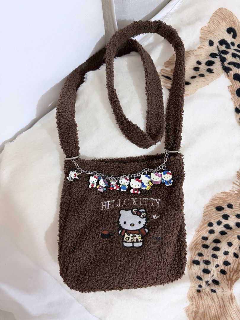 Hello Kitty brown fluffy crossbody bag with charm chain (Category: Cross-body Bags) located in Taguig. Submitted by mengxir20193848 (Listing ID 1471079338, Image 2). Description: - Super soft brown fleece exterior with durable fabric lining - Features cute Kitty embroidery on the front - Detachable silver chain strap adorned with multiple Kitty character charms - Secure zipper closure to keep your essentials safe - Long shoulder strap attached fo