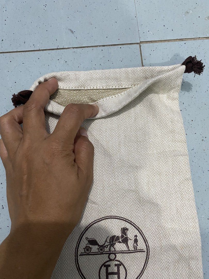 Hermes herringbone dust bag with drawstring (Category: Luxury Bags & Wallets) located in Davao. Submitted by dandeshop (Listing ID 1471089354, Image 2). Description: - 100% Authentic Hermes dust bag - Beige herringbone cotton material with brown silk-screened logo (horse, carriage, and H emblem) - Drawstring closure with dark brown knotted ends - Clean inside and out - Long rectangular shape, ideal for boots, tall items, or smaller bags - From a 