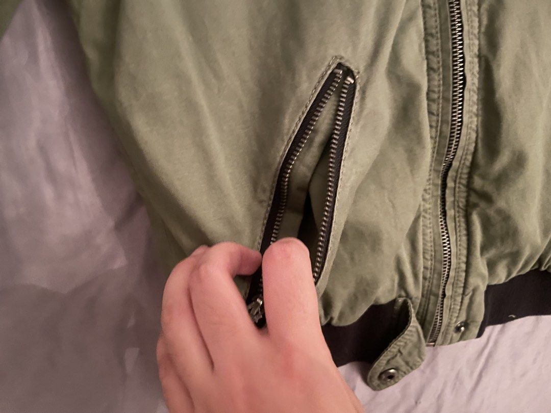 Hollister Olive Green Bomber Jacket Size M (Category: Coats, Jackets and Outerwear) located in Manila. Submitted by azishops (Listing ID 1470991729, Image 3). Description: - Brand: Hollister - Style: Olive green bomber jacket - Size: Medium - Features: Full zip closure, dual zippered waist pockets, soft inner lining - Details: Black ribbed collar, cuffs, and hem - Condition: Clean fabric with no major wear visible.