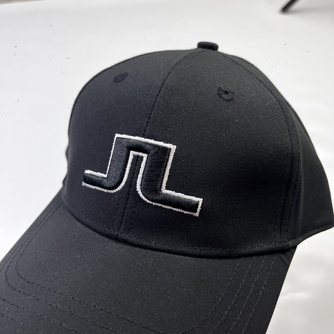 j.lindeberg Black Golf Cap Hat (Category: Caps & Hats) located in Lucena. Submitted by nifty_finds (Listing ID 1470976854, Image 2). Description: - Brand: J.Lindeberg - Condition: Brand new with hang tag attached - Color: Classic black with white embroidered logo on the front - Fit: One size fits most with an adjustable strap and branded metal clasp - Details: Features interior brand and size labels with clean stitching all around.
