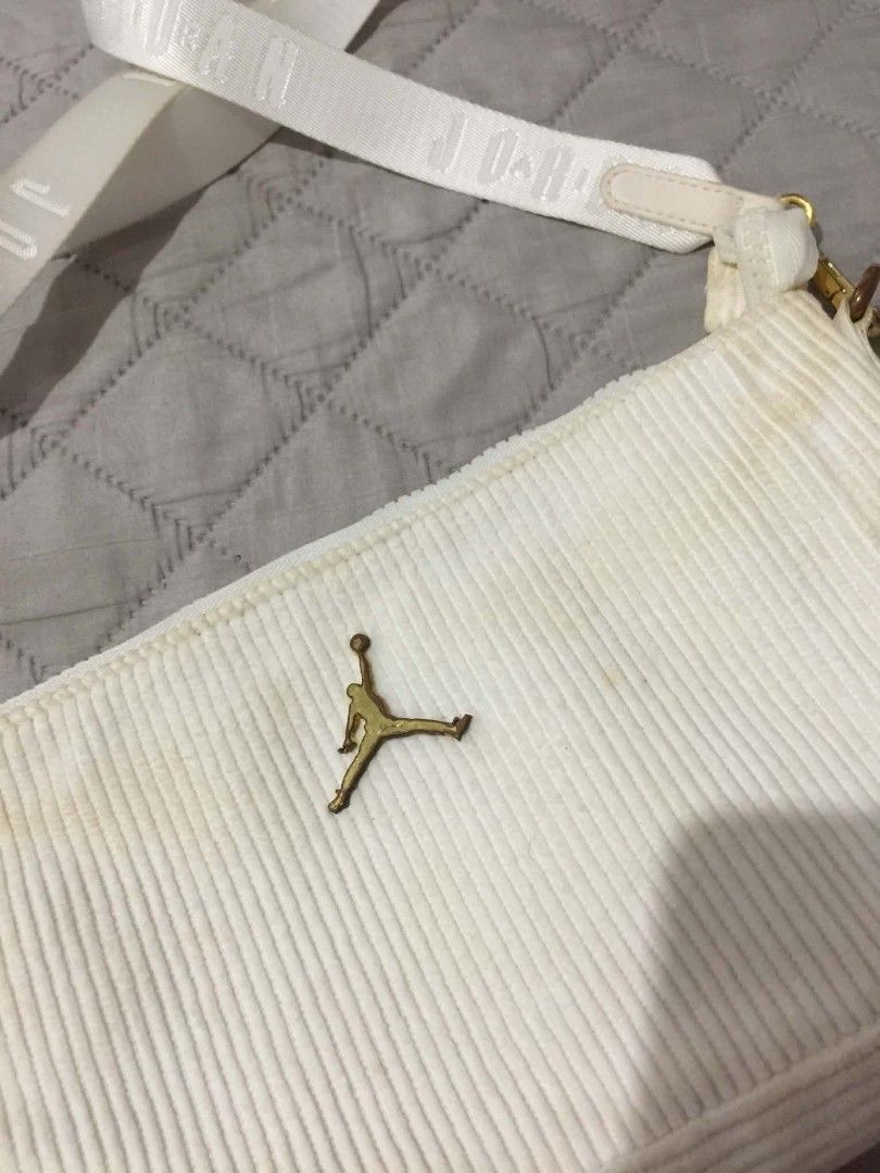 Jordan White Corduroy Shoulder Bag (Category: Shoulder Bags) located in Muntinlupa City. Submitted by prelovedbyanney (Listing ID 1471090441, Image 2). Description: FLAWS ARE SHOWN IN THE PHOTOS HAS YELLOWING ALREADY YELLOWING ISSUE ONLY - Color & Material: White corduroy with a soft ribbed texture - Branding: Iconic gold Jumpman logo on the front and woven Jordan lettering on the strap - Strap: Matching adjustable white strap with lobster clasps