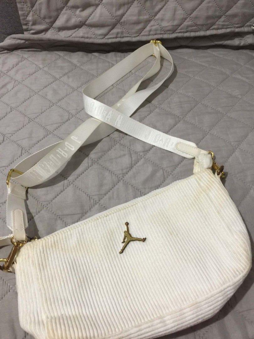 Jordan White Corduroy Shoulder Bag (Category: Shoulder Bags) located in Muntinlupa City. Submitted by prelovedbyanney (Listing ID 1471090441, Image 1). Description: FLAWS ARE SHOWN IN THE PHOTOS HAS YELLOWING ALREADY YELLOWING ISSUE ONLY - Color & Material: White corduroy with a soft ribbed texture - Branding: Iconic gold Jumpman logo on the front and woven Jordan lettering on the strap - Strap: Matching adjustable white strap with lobster clasps
