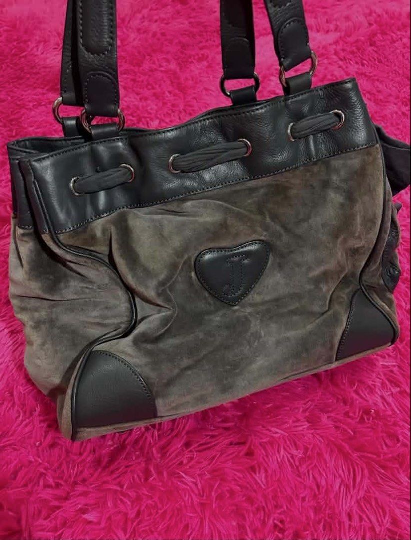 Juicy Couture Brown Suede Tote Handbag (Category: Tote Bags) located in Carmen. Submitted by juicy_gal (Listing ID 1471069642, Image 3). Description: - Brand: Juicy Couture - Material: Brown suede with dark leather trim - Design: Large pink crest graphic on front & heart-shaped 'J' patch on the back - Closure: Drawstring top - Features: Dual shoulder straps, cute side fabric bow detail, and roomy interior - Style: Retro Y2K daily tote.