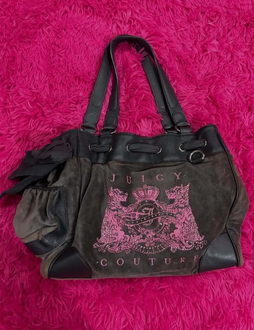 Juicy Couture Brown Suede Tote Handbag (Category: Tote Bags) located in Carmen. Submitted by juicy_gal (Listing ID 1471069642, Image 1). Description: - Brand: Juicy Couture - Material: Brown suede with dark leather trim - Design: Large pink crest graphic on front & heart-shaped 'J' patch on the back - Closure: Drawstring top - Features: Dual shoulder straps, cute side fabric bow detail, and roomy interior - Style: Retro Y2K daily tote.