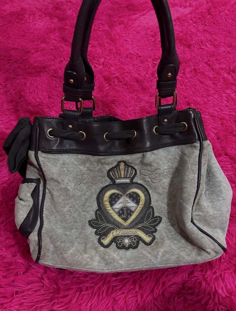 Juicy Couture grey and black velour shoulder bag (Category: Shoulder Bags) located in Carmen. Submitted by juicy_thangs (Listing ID 1471069447, Image 2). Description: - Brand: Juicy Couture - Color: Grey velour with black faux leather trim - Design: Front embroidered crest patch with crown and heart; back heart-shaped patch with raised J logo - Features: Dual top handles, side pocket, and attached ribbon accent - Hardware: Gold-tone throughout - 